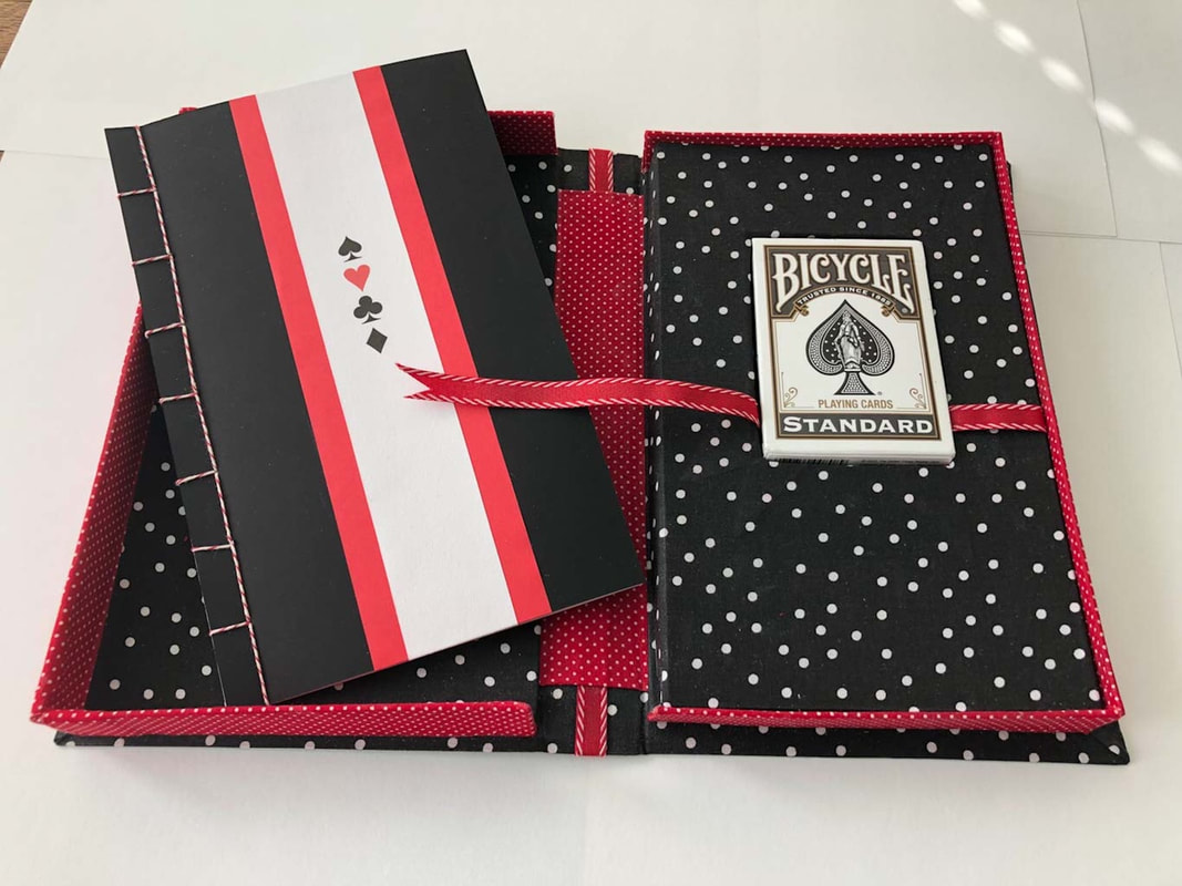 red and black box, open with book on left, deck of playing cards on right